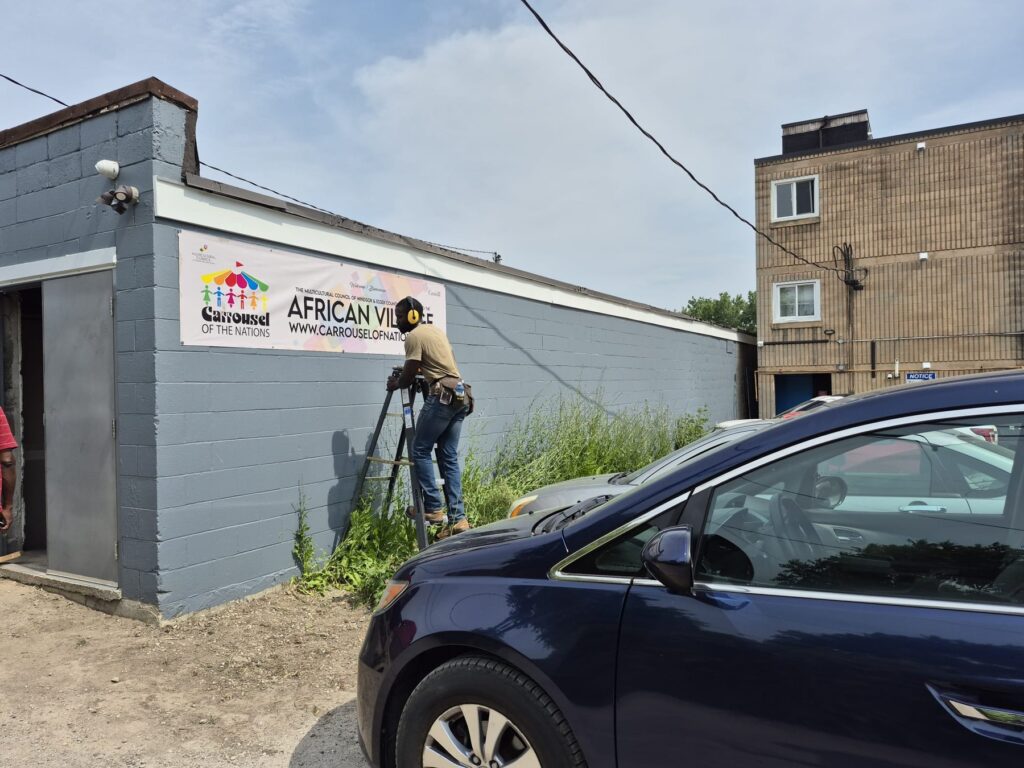 The African Village banner on the venue wall seen from across the parking area.