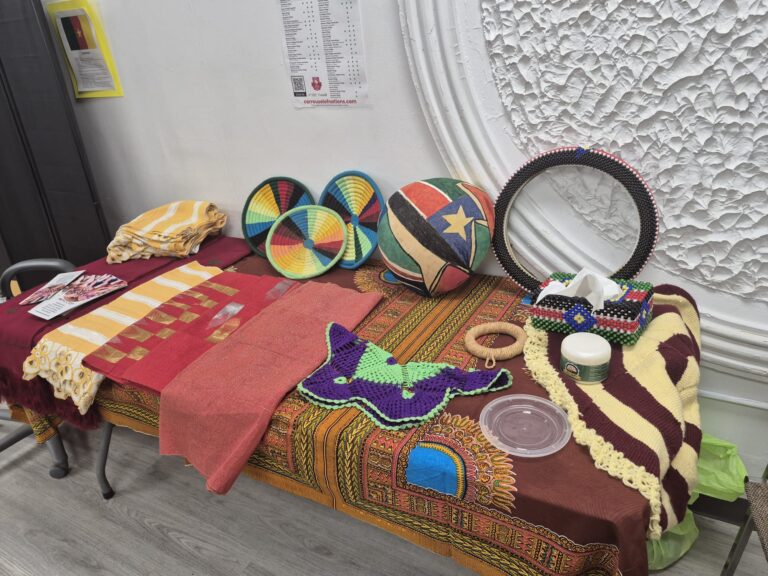 A display table at the BCCEEP Centre laid with patterned cloth, beaded pieces and woven fans