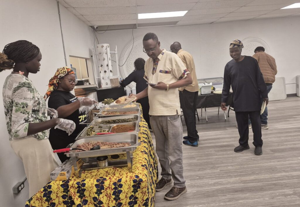 Guests collecting food from chafing dishes on a yellow patterned cloth at BCCEEP Hall.