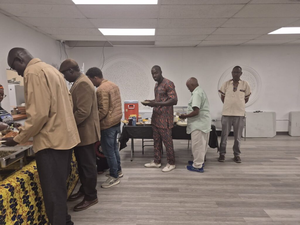 A line of guests waiting along the length of the serving table at BCCEEP Hall, plates in hand.