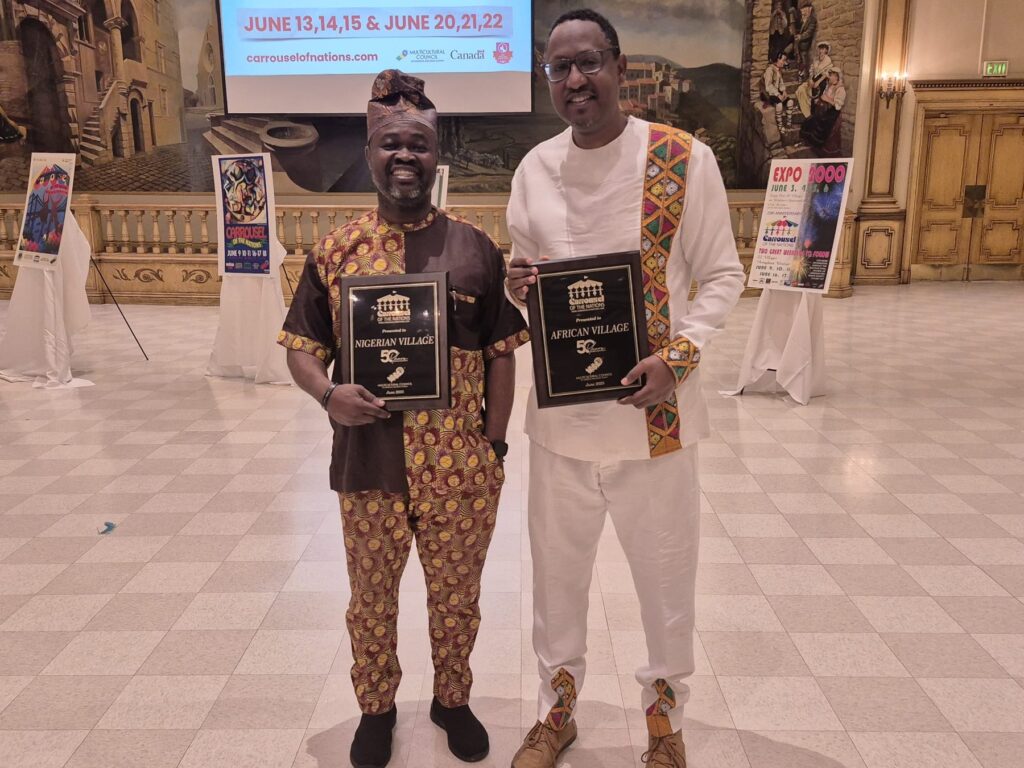 Two men holding framed award plaques in the Ciociaro Club ballroom.