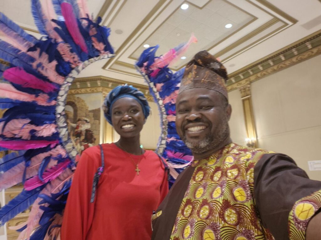 A guest wearing a large pink and blue feathered headdress standing beside another guest at the Ciociaro Club.