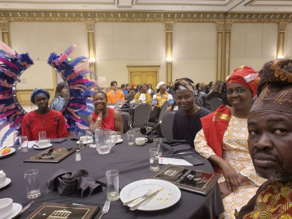 Guests seated at round banquet tables at the Ciociaro Club, some in feathered headdresses.