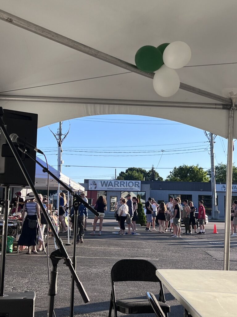 Green and white balloons tied to the marquee frame at the Nigerian Village, looking out to the crowd gathered along Walker Road in Windsor