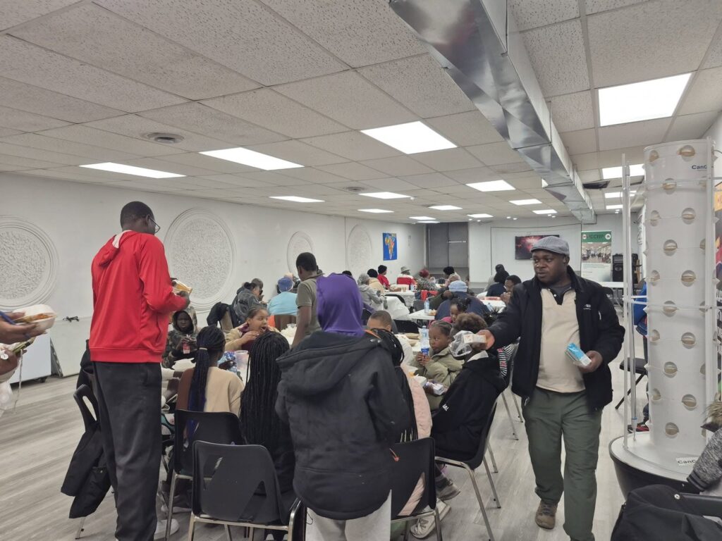 A wide view of the room with guests seated at the tables, a tall white planting tower against the wall.