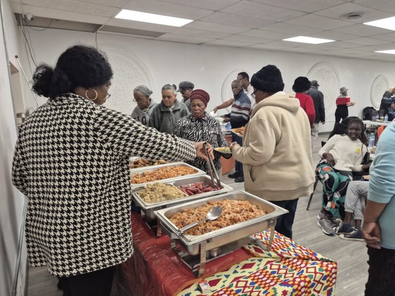 Plates being filled at the serving table while guests wait alongside at the November gathering.
