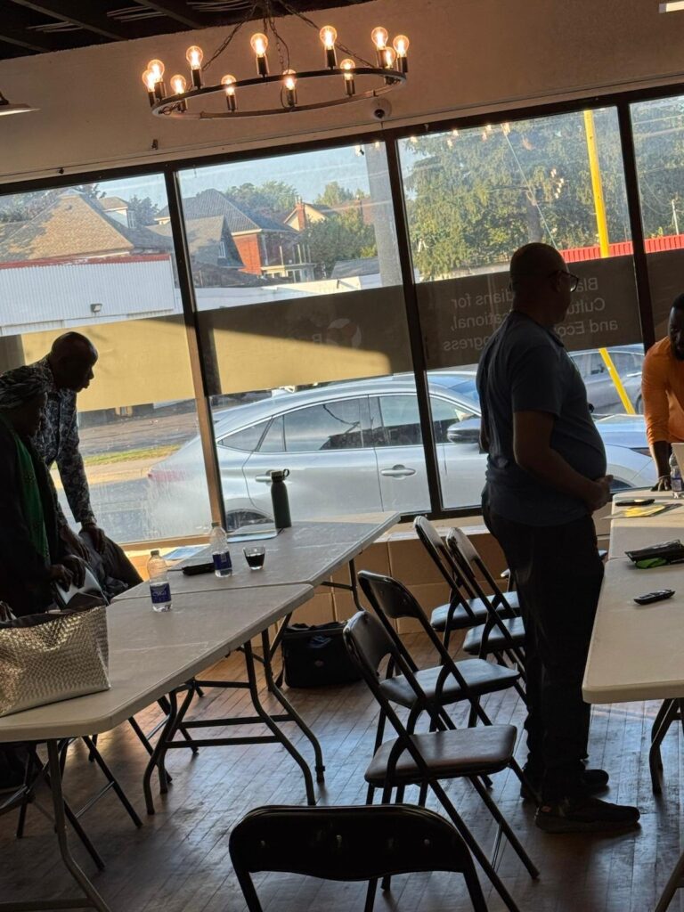 Participants gathered near the front window with a table of supplies, cars visible outside.