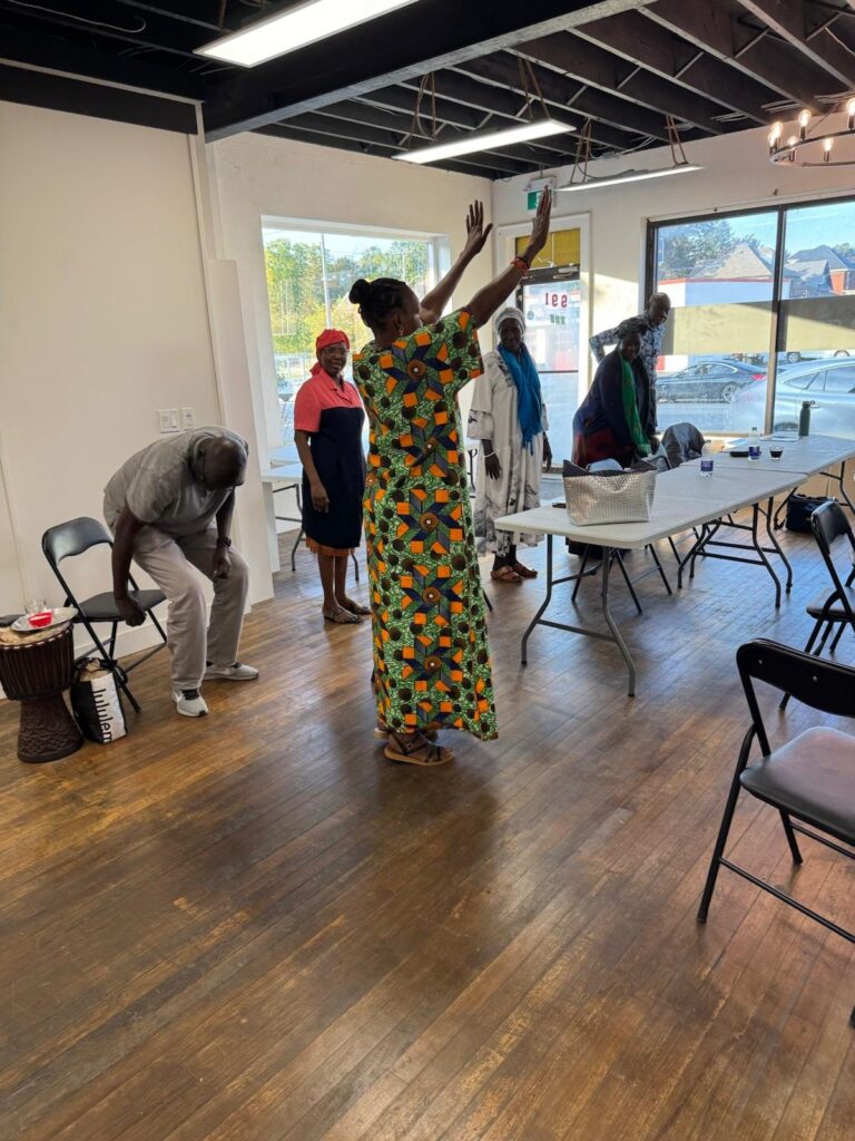 A participant reaching one arm overhead during a standing stretch while another bends toward the floor.